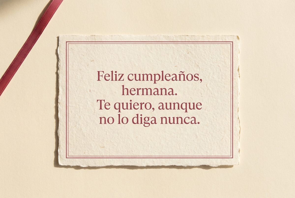 Tarjeta de cumpleaños de papel crema hecho a mano, con borde deckle y un filete impreso en rosa oscuro, fotografiada en plano cenital. En la tarjeta se lee «Feliz cumpleaños, hermana. Te quiero, aunque no lo diga nunca.». Al lado, una cinta de raso rosa que baja desde la esquina superior izquierda.